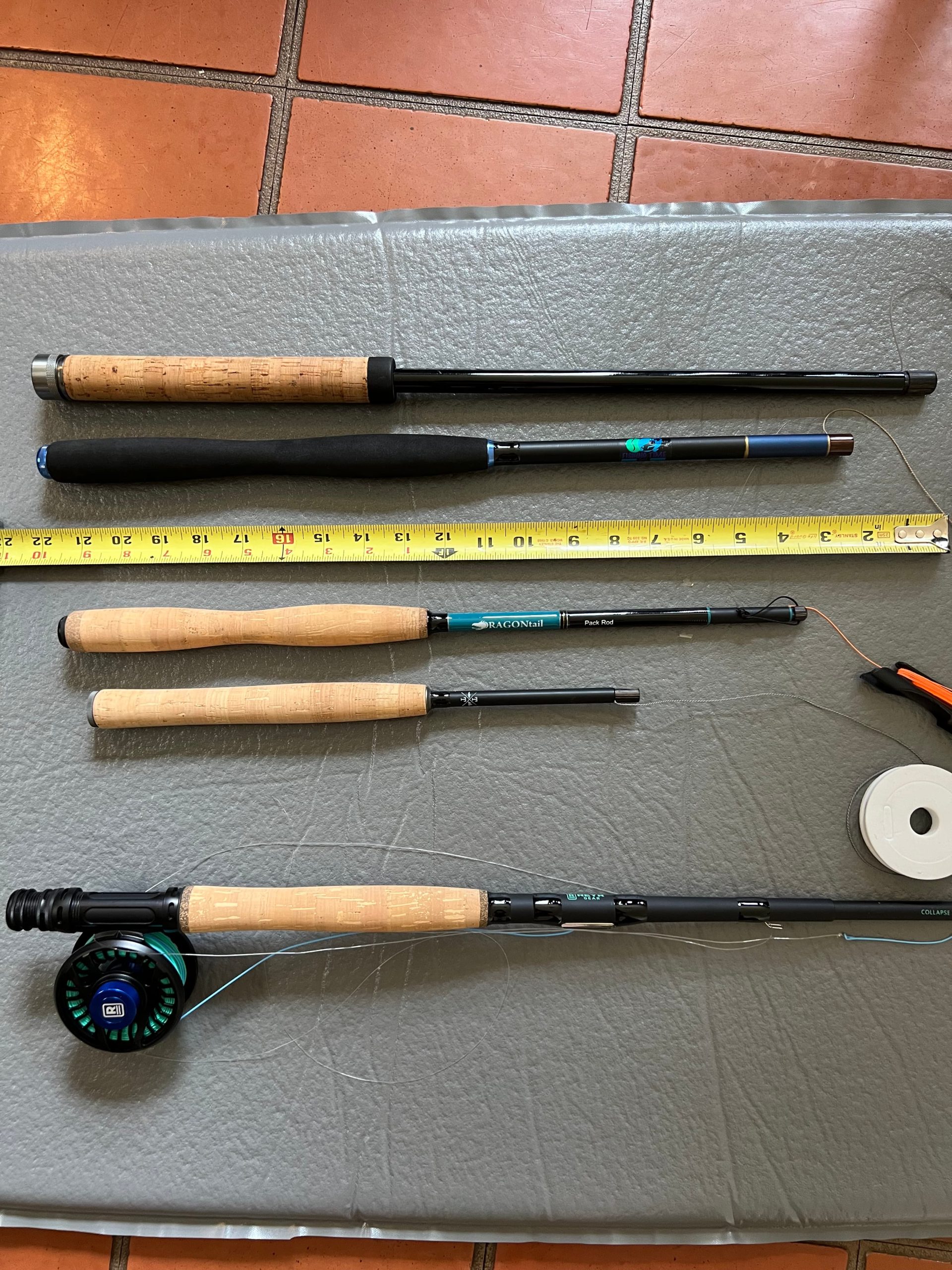 Five fly-fishing rods with a tape measure showing length